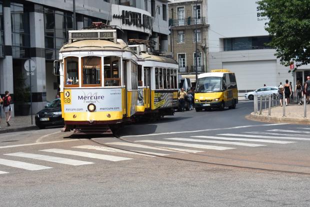 Yellow classic refurbished tram 28 on road heading in the direction of Prazeres.